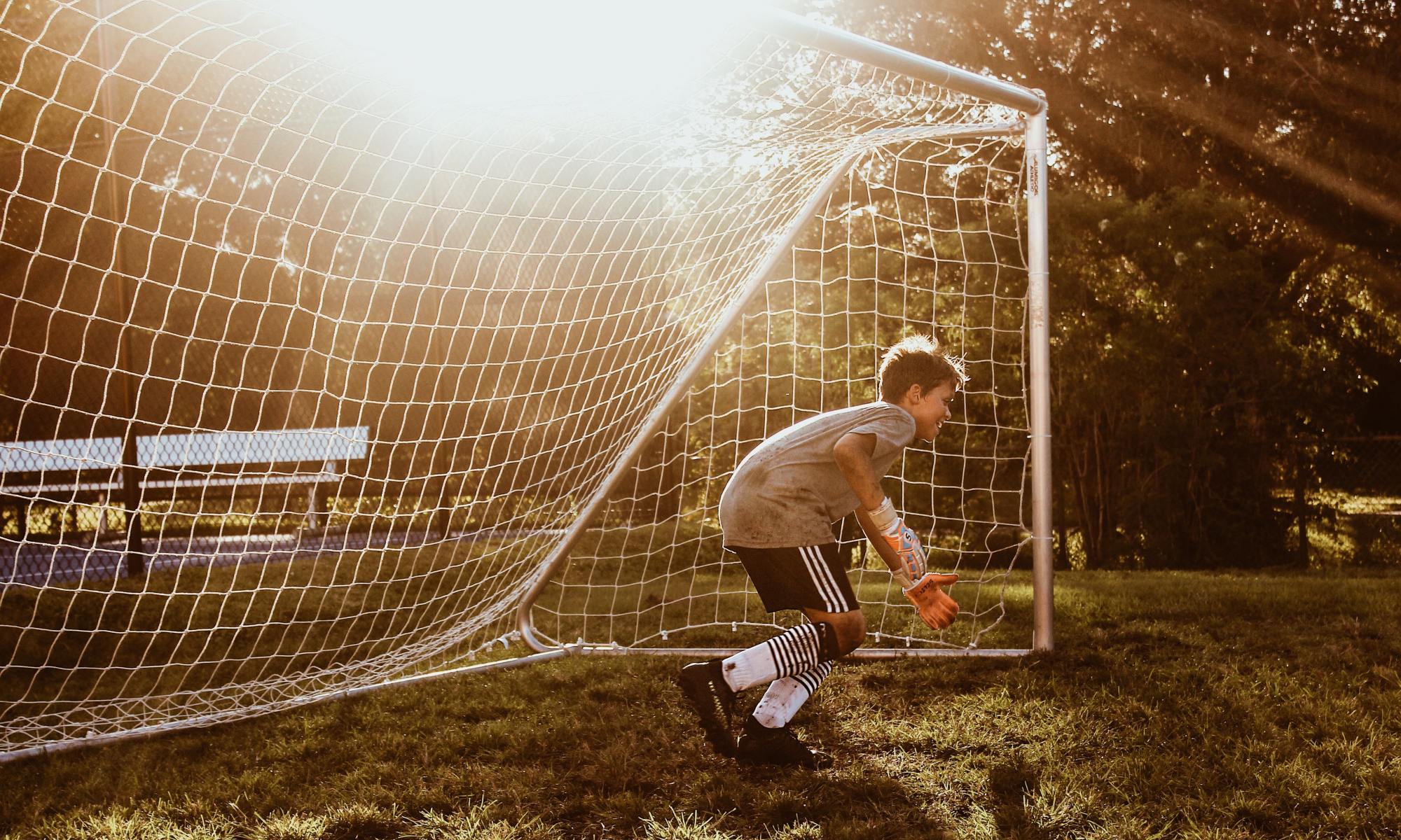 Photo of football (soccer) goalkeeper getting ready to stop a strike on a sunny day.